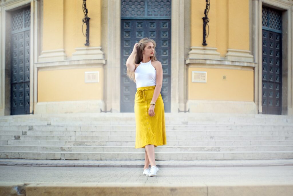 woman wearing yellow and white dress standing beside building during daytime, midi skirts outfits