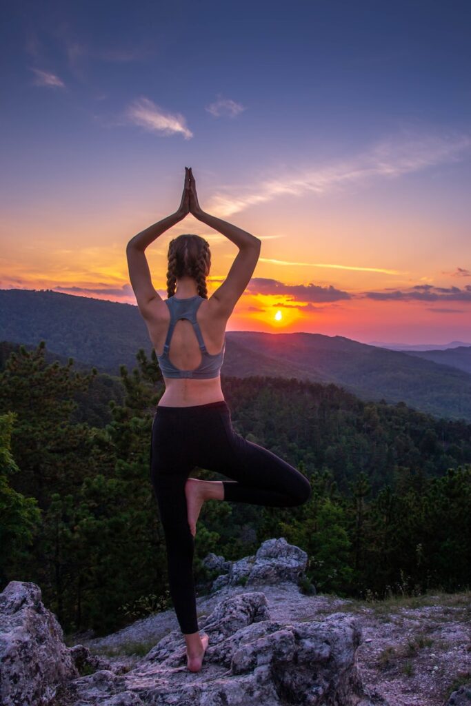 woman in black leggings standing on rock formation during sunset, feminine energy