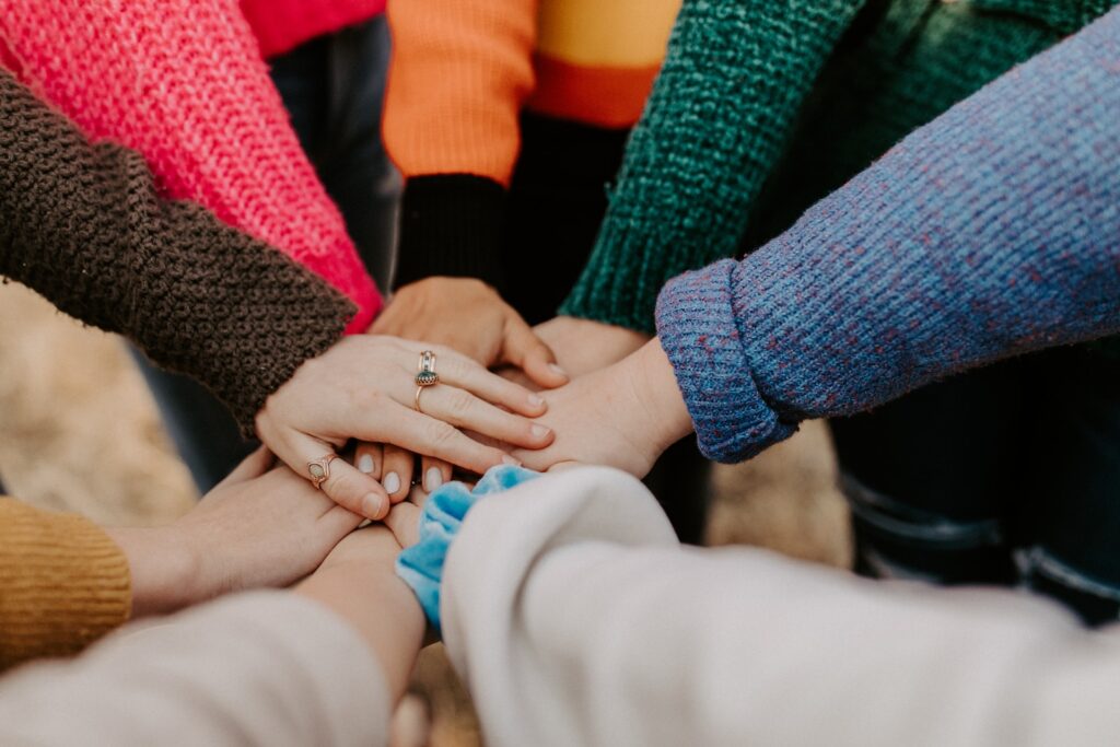 person in red sweater holding babys hand, feminization journey