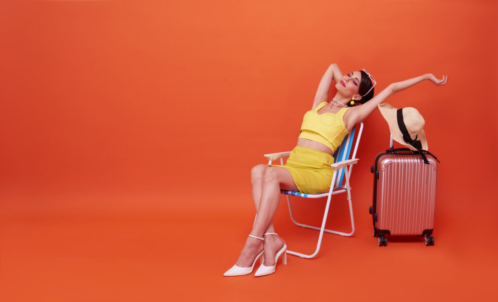 Self-care After The Holidays: Ways to Embrace Yourself In The New Year 2 beautiful woman relax sitting beach chair with suitcase studio summer orange background scaled 1