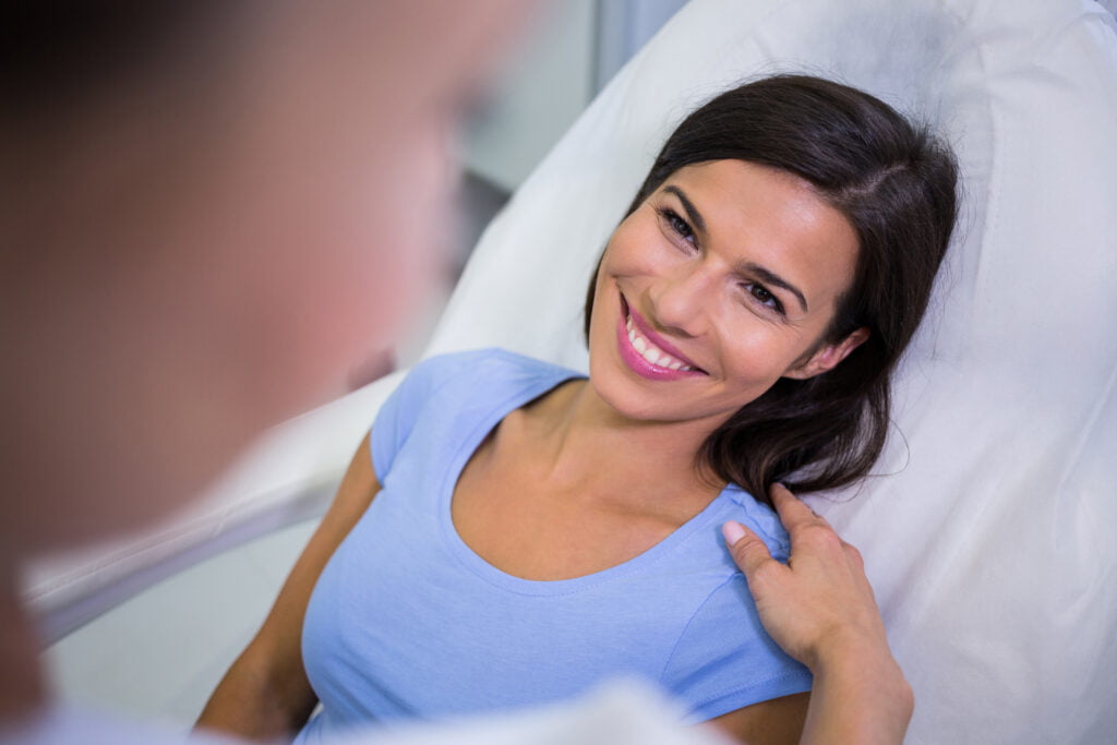 Hoeveel kost het om te herstellen van een gezichtsfeminisatiechirurgie (FFS)? vrouwelijke patiënt glimlacht terwijl ze met een arts praat