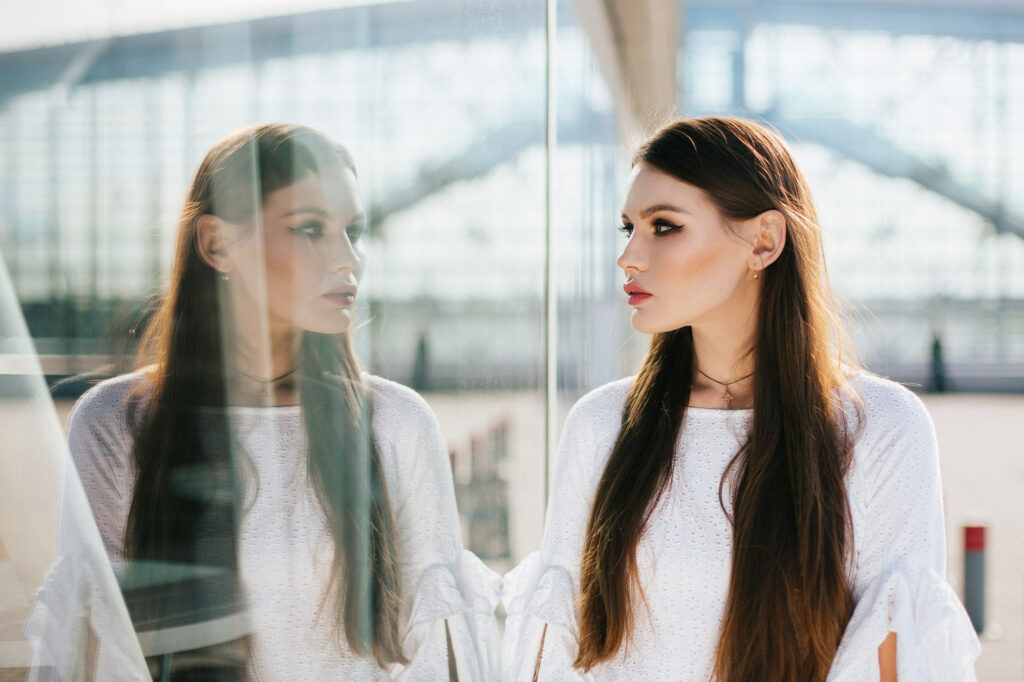 beautiful woman with long hair looks her reflection modern glass building