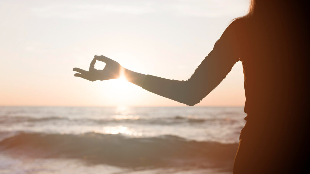 woman meditating sunset beach