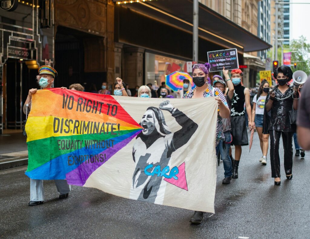 a group of people walking down a street holding a rainbow flag